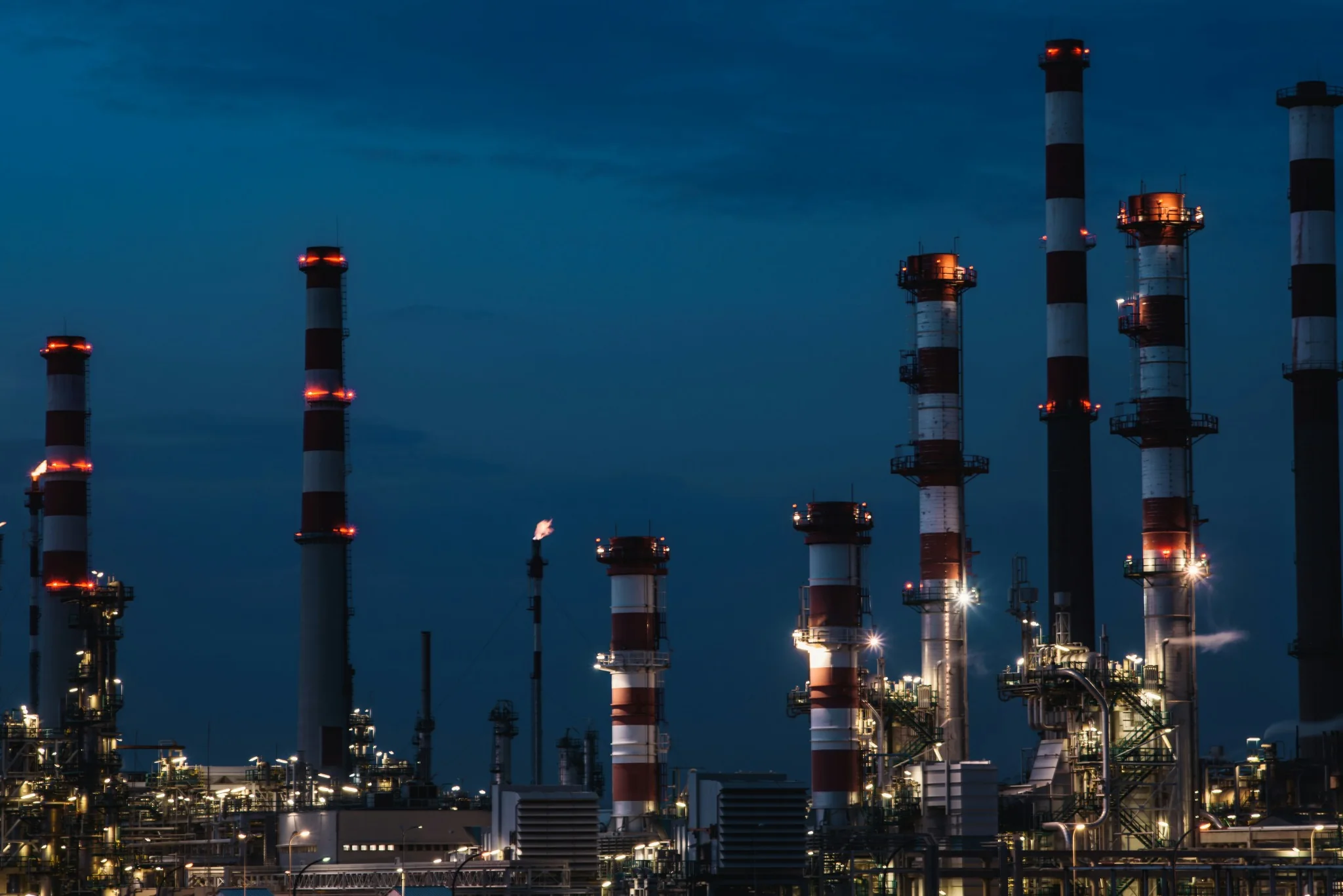 Illuminated process towers and equipment at an industrial plant at dusk.