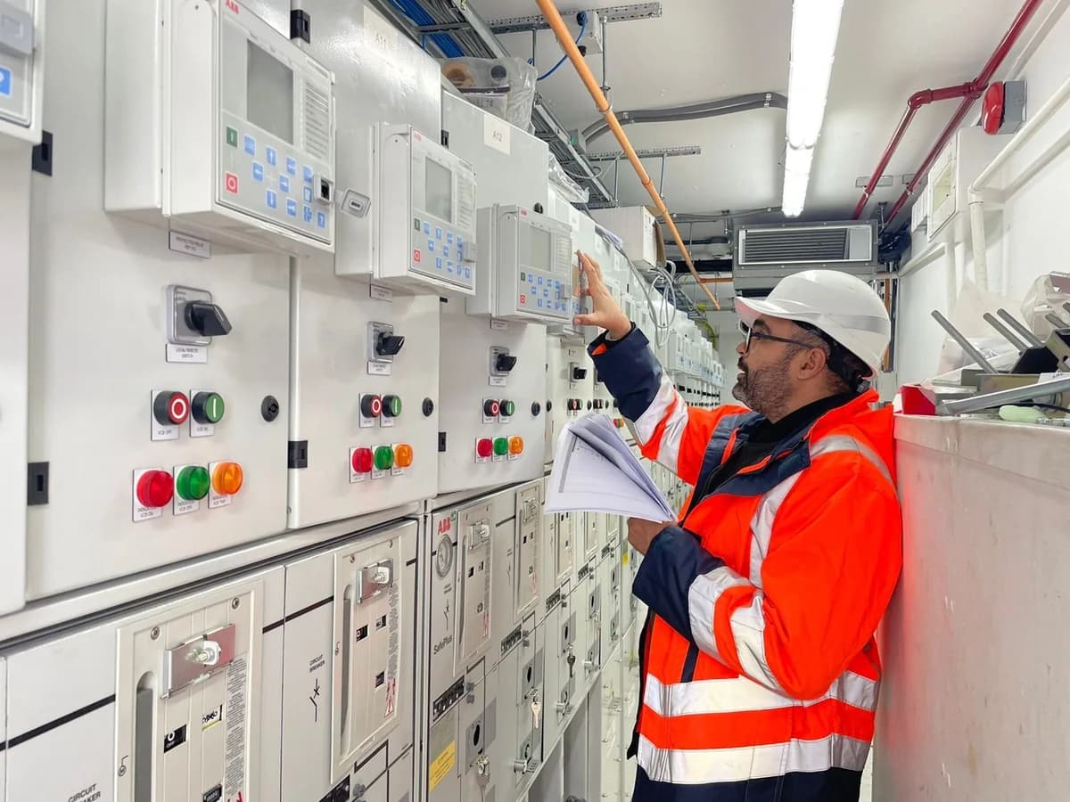 Engineer inspecting protection and control panels in electrical switchgear.